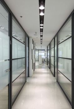 an empty hallway with glass doors and lights on the ceiling is seen in this image