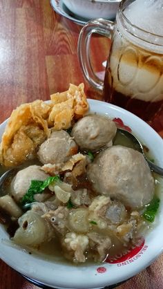 a white bowl filled with food next to a glass of beer