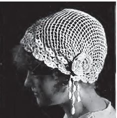 a black and white photo of a woman wearing a crochet hat with flowers on it