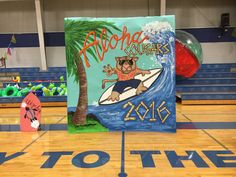 a sign on the floor in front of a basketball court with an image of a man riding a surfboard