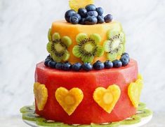 a fruit cake with kiwis, blueberries, and bananas on the top