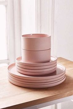 a stack of pink plates sitting on top of a wooden table