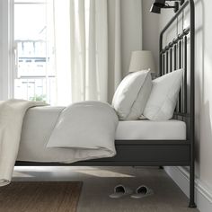 a bed with white sheets and pillows on top of it next to a pair of slippers