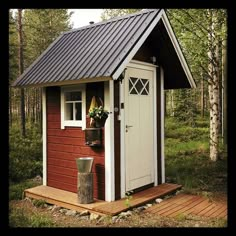 a small red and white shed in the woods