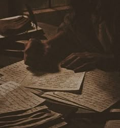 a person sitting at a table with lots of papers and writing utensils on it