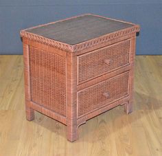 a wicker night stand with two drawers on the bottom and one drawer open, sitting on a wooden floor