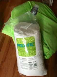 a bag of polyfil sitting on top of a wooden floor next to a green pillow