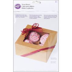 an open box with three donuts wrapped in red ribbon and tied around the top