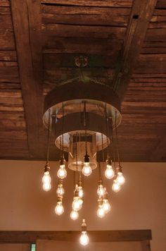 a chandelier hanging from the ceiling in a room with wooden beams and light bulbs