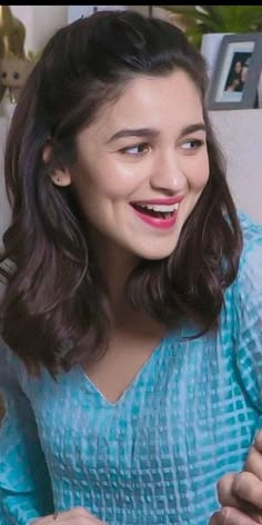 a woman is smiling and holding a plate with food on it while looking at the camera