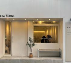 two people are standing in the window of a restaurant that is white and has black lettering on it