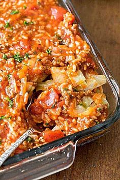 a casserole dish with meat and vegetables in it on a wooden table, ready to be eaten