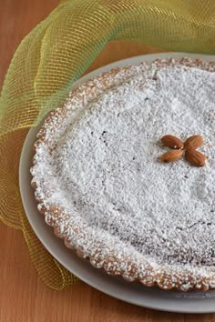 a white plate topped with a cake covered in powdered sugar and two almonds