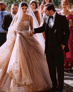 the bride and groom are walking down the aisle with their guests in the back ground