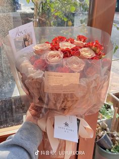 a bouquet of roses wrapped in cellophane and sitting on a window sill