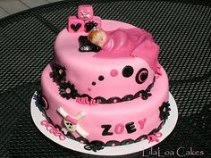 a pink and black cake with a baby doll on it's top sitting on a table