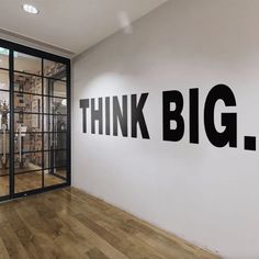 the words think big are painted on a white wall in an empty room with wooden floors