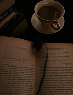 an open book sitting on top of a table next to a cup of coffee and books