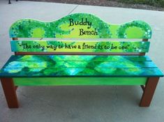 a bench painted with the words buddy and bench on it's back, sitting in front of a sidewalk