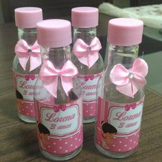 four bottles with pink bows on them sitting on a table