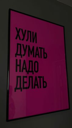 a pink sign hanging on the side of a wall with black lettering in russian and english