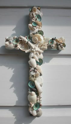 a cross made out of seashells is hanging on the side of a building