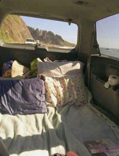 there is a small bed in the back of a truck with pillows and blankets on it