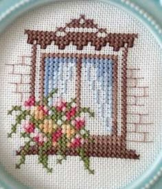 a cross stitched picture of a window with flowers