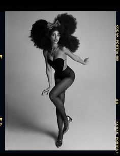 a black and white photo of a woman in tights with an afro on her head