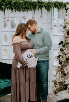 a man and woman standing in front of a christmas tree