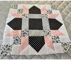 a black and white patchwork quilt on top of a bed with polka dotty