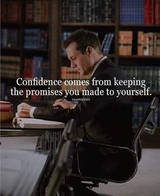 a man sitting at a desk in front of a book shelf with a quote on it