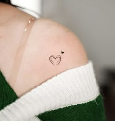 a woman with a small heart tattoo on her shoulder