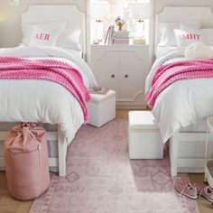 two white beds with pink blankets and pillows