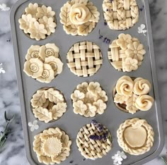 twelve pies are arranged in the shape of flowers on a baking tray with lavender sprigs