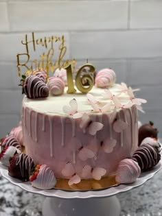 a birthday cake with pink frosting and chocolate covered strawberries