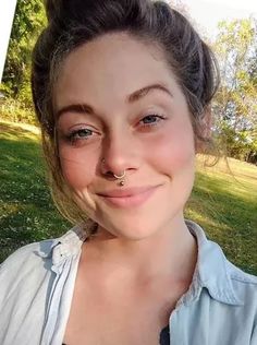 a woman with a nose piercing smiling at the camera