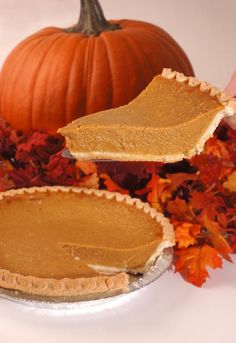 two pumpkin pies sitting on top of a white plate next to leaves and flowers