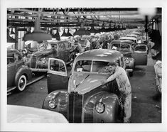 an assembly line with old cars and men working on them