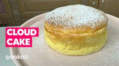 a cake sitting on top of a white plate covered in powdered sugar next to a pink sign that says cloud cake