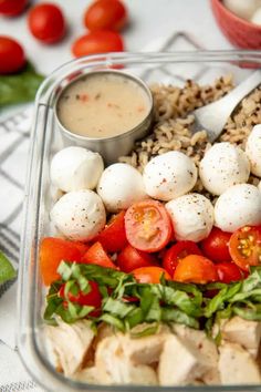 a meal in a plastic container with tomatoes and mozzarella on the side, along with other food items