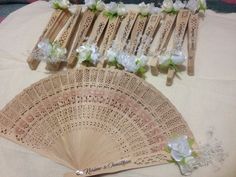 an arrangement of flowers and wooden fan on a table