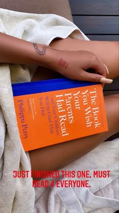 a woman's arm wrapped in a towel with an orange book on it