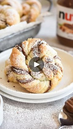 powdered sugar covered pastry on a white plate next to other pastries and spoons