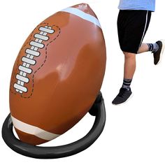 an inflatable football sitting on top of a black stand next to a person