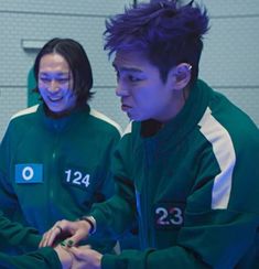 three young men standing next to each other in front of a computer screen with numbers on it