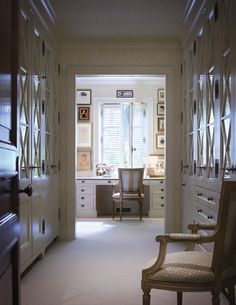 an empty hallway leading to a desk and chair in a room with many pictures on the walls