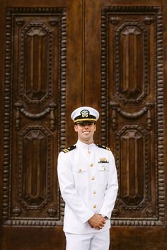 a man in a naval uniform standing in front of a wooden door