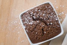 a close up of a cake in a pan on a table with powdered sugar