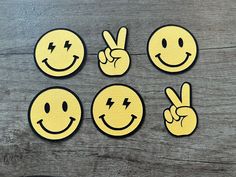 four yellow smiley face patches with one peace sign and the other two fingers in the air